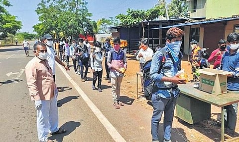 Migrant workers from Goa, who arrived on foot at Honnihal village near Belagavi on Saturday, receive food packets from villagers