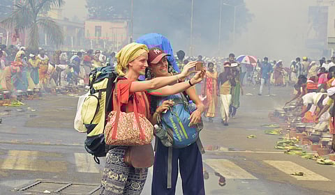 Foreign tourists taking a selfie at Thampanoor ahead of Attukal Pongala in Thiruvananthapuram. (Photo | B P Deepu, EPS)