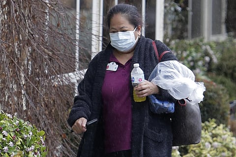 A worker wears a mask at the Life Care Center in Kirkland, Wash., near Seattle, walks near a UPS truck during a package delivery, Monday, March 2, 2020. (Photo | AP)