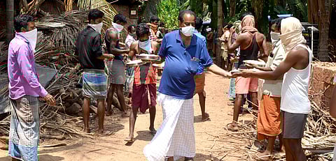 Abdul Khader with the migrant workers during lunchtime at Porapad, a village in Trikaripur panchayat. (Photo | EPS)