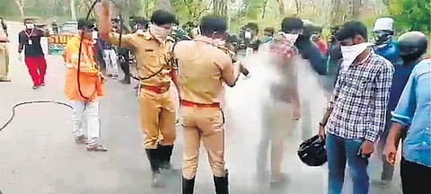 Kerala Fire and Rescue Dept officers spraying disinfectant on people who came from Karnataka in Wayanad