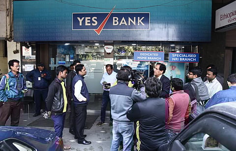 Customers gather outside the YES bank branch at Janpath in New Delhi, a day after RBI put a limit on monthly withdrawals for account holders at the bank. The bank is in midst of financial troubles and the RBI has taken charge of its management. (Photo | P