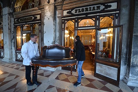 Waiters move tables and chairs inside the Cafe Florian in Saint Mark Square just before at 18 o'clock in Venice on March 8, 2020, after millions of people were placed under forced quarantine in northern Italy as the government approved drastic measures in