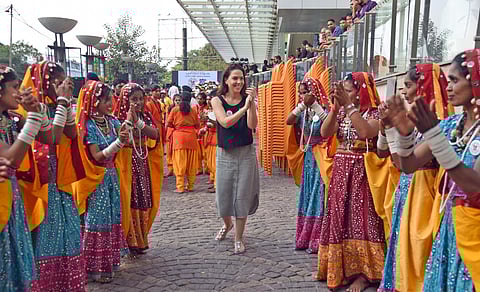 A foreigner shares a light moment with folk artistes during Women’s Day celebrations organised by Bengaluru City Police East Division at 1 MG mall. (Photo | Nagaraja Gadekal, EPS)