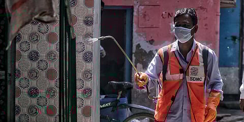 SDMC health workers spray disinfectants during a government-imposed lockdown as a preventive measure against the coronavirus at Sector 7 in New Delhi's RK Puram. (Photo| ANI)