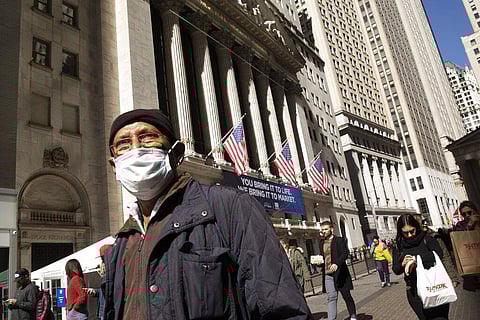 In this Monday, March 9, 2020 file photo, a man wears a mask as he walks past the New York Stock Exchange, amid concerns of the COVID-19 coronavirus outbreak. (Photo | AP)