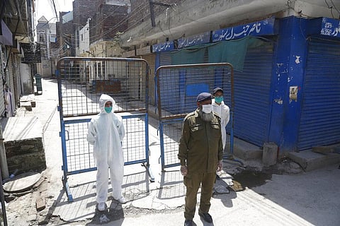Pakistan volunteers and a police officer stand guard outside the area which authorities sealed after a group of people tested positive for the new coronavirus, Friday, April 10, 2020 in Lahore, Pakistan. (Photo | AP)
