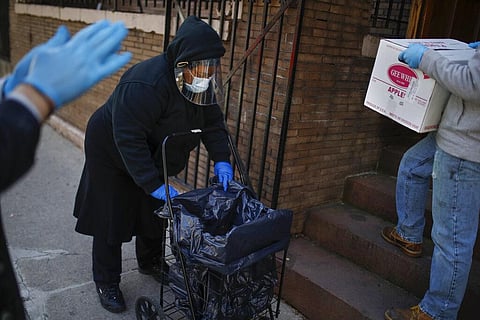 A visitor wearing personal protective equipment prepares her cart before receiving a box of donated food at the Covenant Mercy Food Pantry, Saturday, April 11, 2020, in New York. (Photo | AP)