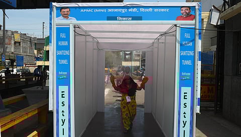 A women walks through a sanitizing tunnel after its installation during the nationwide lockdown to curb the spread of coronavirus at Azadpur Mandi in New Delhi Friday April 10 2020. (Photo | Parveen Negi/EPS)