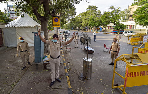 A police officer sanitises himself in front of a fan with a sprayer installed by Barakhamba Road Police Station amid a nationwide lockdown in the wake of coronavirus pandemic near Bengali market area in New Delhi. (Photo | PTI)