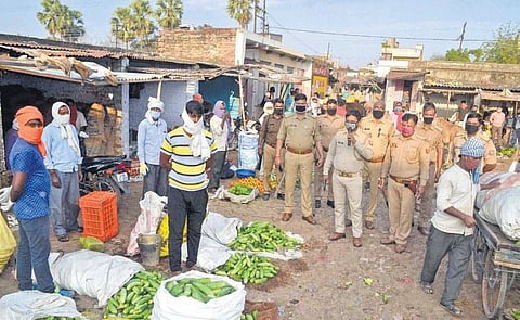 Police personnel maintain social distance as they make announcements at a vegetable market in Varanasi. (Photo | PTI)
