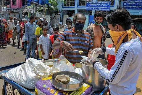 Volunteers distribute food to the needy and homeless people during the nationwide lockdown in the wake of coronavirus pandemic in Kolkata Thursday. (Photo | PTI)