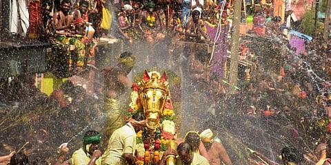 Devotees splash water as Lord Kallazhagar enters the Vaigai river as part of Chithirai Festival of the famous Meenakshi Temple in Madurai. (File Photo | PTI)