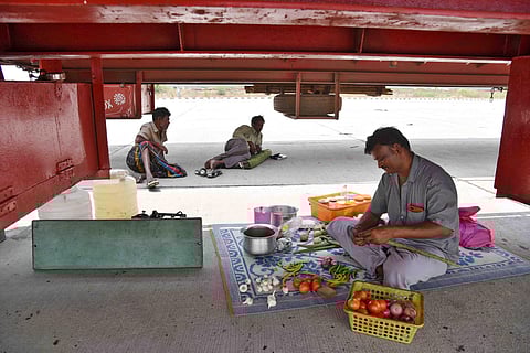 As hotels and other sources of food are closed due to lockdown, truck drivers transporting essential goods prepare food by themselves. A driver cooking under his truck near Gummidipoondi toll gate on Thursday | R Satish Babu