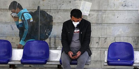 Men wearing face masks against coronavirus sits at a bus stop in Niavaran in Tehran. (Photo | AP)
