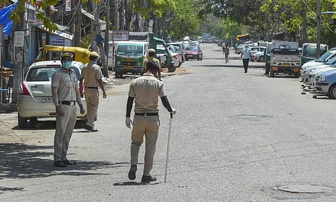 Security personnel stand guard on a deserted road at C block Jahangirpur area identified as COVID-19 hotspot during the nationwide lockdown to curb the spread of coronavirus in New Delhi Sunday. (Photo | PTI)