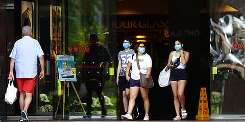 People wearing protective face masks exit a mall along the Orchard Road shopping belt in Singapore. (Photo | AP)