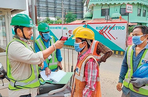 A Kochi Metro Rail Ltd employee thermally screening construction workers at  the site as work resumed on Wednesday