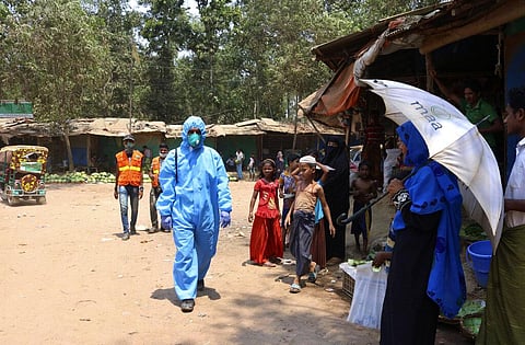 In this April 15, 2020, photograph, a health worker from an aid organization walks wearing a hazmat suit at the Kutupalong Rohingya refugee camp in Cox's Bazar, Bangladesh. (Photo | AP)