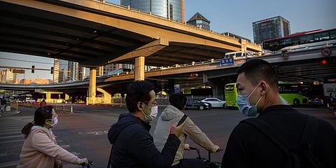 People wear face masks to protect against the spread of the new coronavirus as they wait to cross an intersection in Beijing. (Photo| AP)