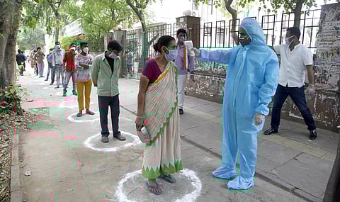 A woman being checked by thermal device during a food distribution programme organised by Delhi Pradesh Congress committee in New Delhi. (Photo | Anil Sakhya, EPS)