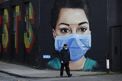 A man wearing a face mask and gloves to protect from coronavirus walks past a recently painted mural by professional street artist David Speed and the Graffiti Life collective to show appreciation for the people who work in the NHS in London. (Photo | AP)