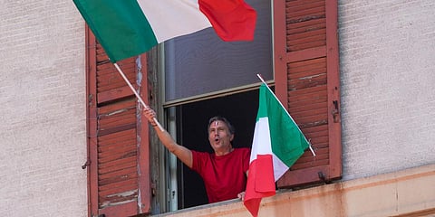 A man waves the Italian flag as he chants from his window on the occasion of the 75th anniversary of Italy's Liberation Day, in Rome. (Photo| AP)