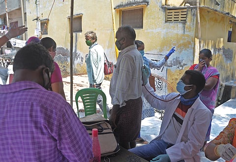 A doctor checks a person during a medical camp organized by VMC to look for symtomatic persons and provide general medicines for symptom of Coronavirus at Chittinagar in Vijayawada on Friday. (Photo | EPS/Prasant Madugula)