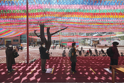 Buddhist believers wearing face masks to help protect against the spread of the new coronavirus line up while maintaining social distancing during a service at the Chogyesa temple in South Korea. (Photo | AP)