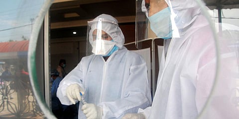 Health officials use a swab to collect a sample from a journalist for COVID-19 test. (File photo| ANI)