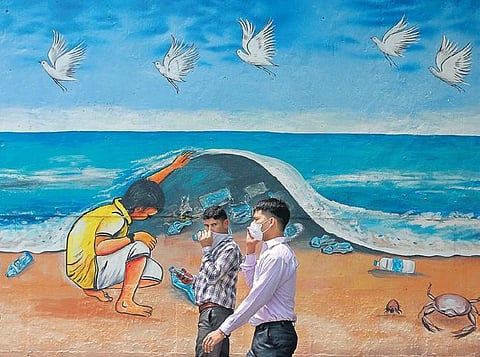 Men wearing face masks walk past a graffiti during the lockdown | Shekhar yadav