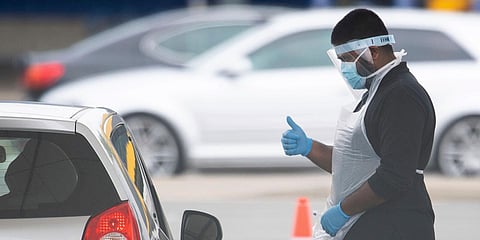 A tester, wearing a mask to protect against coronavirus, gestures to a driver at a drive through coronavirus testing site at IKEA in Wembley, north London. (Photo| AP)