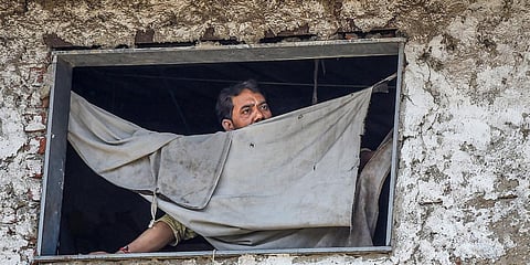 A man looks on through the window of his house during a nationwide lockdown in the wake of coronavirus pandemic at Dharavi in Mumbai. (Photo| PTI)