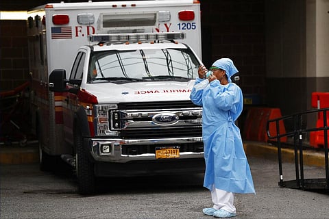 An emergency room nurse dons her face protectors after taking a break in a driveway for ambulances and emergency medical services vehicles outside Brooklyn Hospital Center's emergency room, Sunday, April 5, 2020, in New York, during the coronavirus crisis
