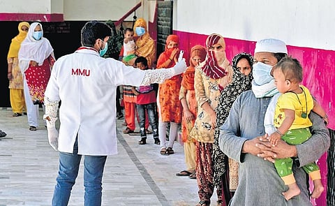A medic checks the temperature of people at a COVID-19 quarantine facility in Prayagraj, UP | PTI