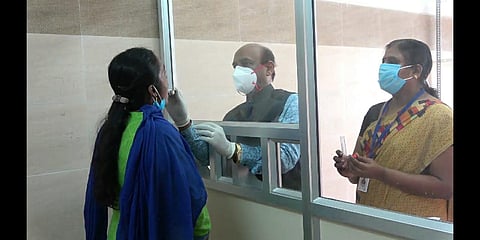 Dean of Pudukkottai Medical College demonstrates the newly built partition for doctors to take swabs from patients suspected to have COVID-19 (Photo | Express)