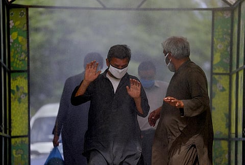 People walk through a disinfecting tunnel setup at an entrance to a wholesale vegetable and fruit market to help curb the spread of the coronavirus, in Islamabad, Pakistan, Monday, April 6, 2020. (Photo | AP)
