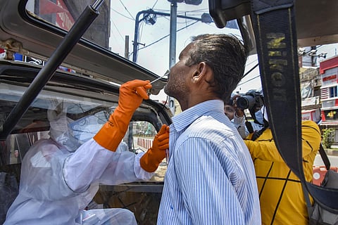 A health worker wearing protective suit collects sample from a resident for COVID-19 test at a camp. (Photo | PTI)