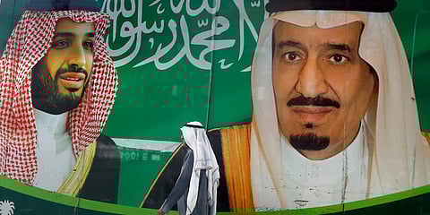A man walks past a banner showing Saudi King Salman (R) and his Crown Prince Mohammed bin Salman, outside a mall in Jeddah. (Photo| AP)