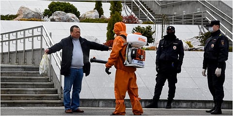 Emergencies personnel wearing protective gear spray disinfectant on a man at the site of a fire at the Saint George hospital in Saint Petersburg. (Photo| AFP)
