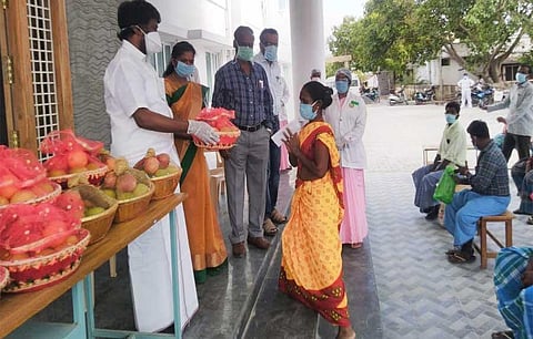 Perambalur MLA R Tamilselvan presents fruit to a woman patient who discharged from the isolation ward in Perambalur GH on Tuesday. (Photo | EPS)