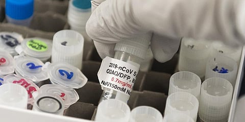 A senior doctor lifts a vial with a potential coronavirus, COVID-19, vaccine at Novavax labs in Rockville, Maryland. (Photo| AFP)