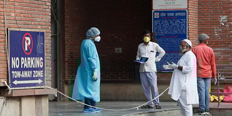 A healthcare worker of LNJP in a PPE kit interacts with people. (Photo| Anil Shakya, EPS)