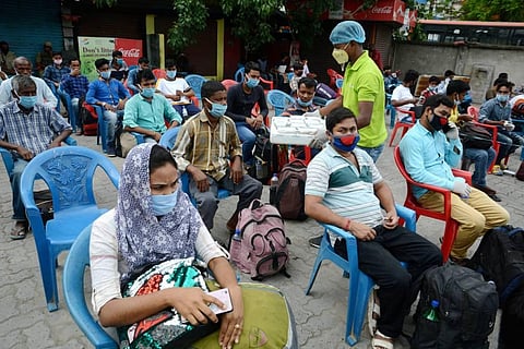 A volunteer distributes food among the passengers waiting to board a bus for their hometown during ongoing COVID-19 lockdown in Guwahati. (Photo | PTI)