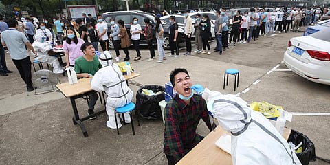 Workers line up for medical workers to take swabs for the coronavirus test at a large factory in Wuhan. (Photo| AP)
