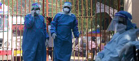 Health workers wearing protective gear stand near an ambulance carrying the dead body of a victim who died from the COVID-19 before the last rites at Nigam Bodh Gath in New Delhi on Saturday. (Photo | Shekhar Yadav/EPS)