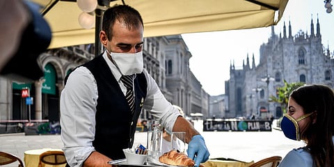 Two girls have breakfast served at a bar in front of the gothic Cathedral in Milan, Italy. (photo| AP)