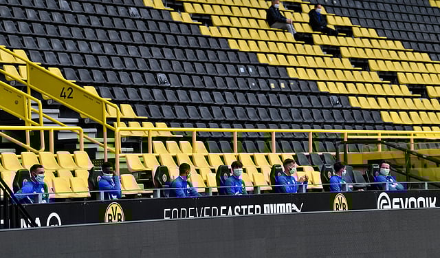 Schalke substitutes sit on the bench wearing masks and maintaining social distancing during their match against Borussia Dortmund on Sunday. Wild celebrations and happy hugs are not part of the 'beautiful game' anymore. (Photo | AP)