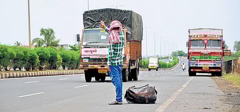 A migrant ask for a lift from trucks on the Pune-Bengaluru NH near Belagavi