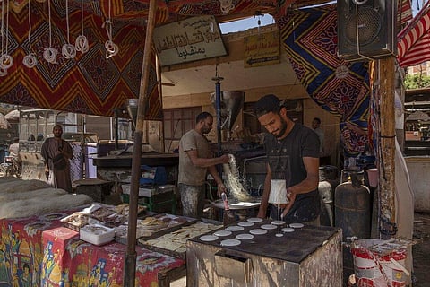 28-year-old football defender Mahrous Mahmoud, right, makes Ramadan sweets at a souq, in Manfalut, a town 350 kilometers (230 miles) south of Cairo in the province of Assiut, Egypt. (Photo | AP)